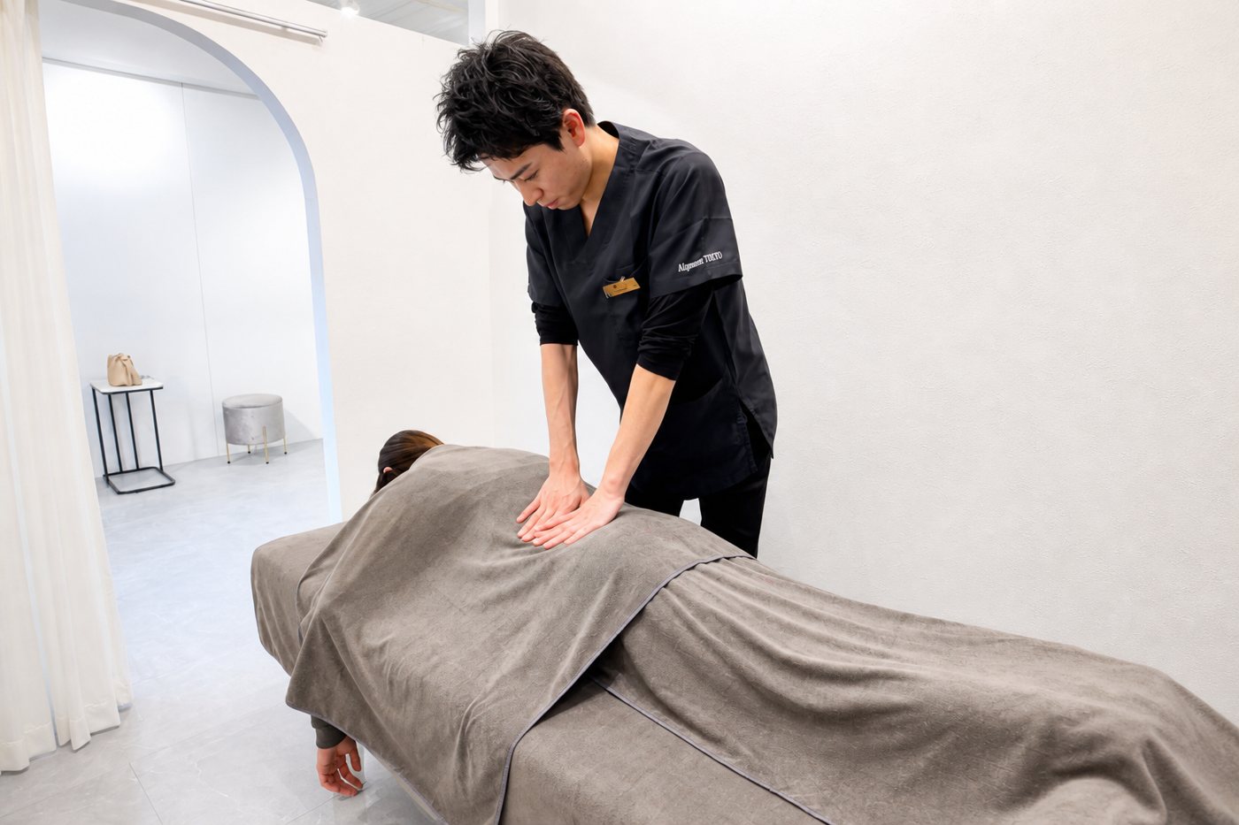 美容整体 — うつ伏せのお客様の背中を両手で整える施術イメージ